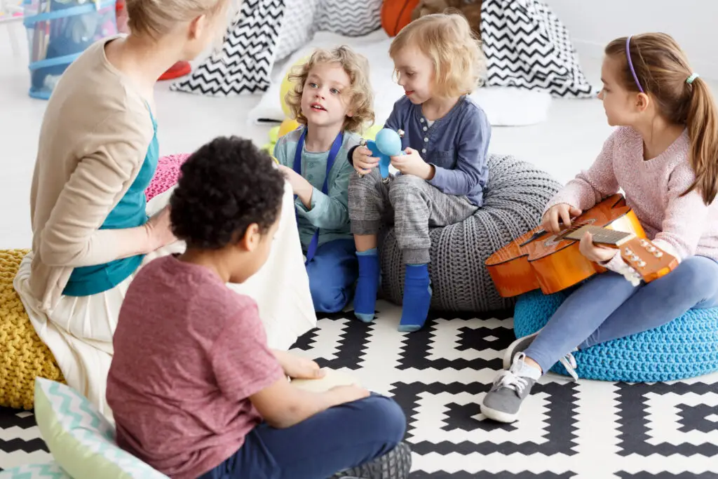 Preschool kids sitting on a carpet in kindergarten learning music